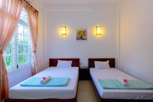 two beds in a room with a window at Mango Garden Hoi An Homestay in Hoi An