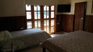 una camera con due letti, una TV e una finestra di Hotel Rex a Chitré