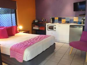 a bedroom with a large bed and a kitchen at Pink Flamingo Resort in Port Douglas