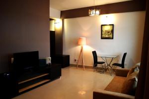 uma sala de estar com uma televisão e uma mesa com cadeiras em Hotel Grand Tizu em Dimāpur