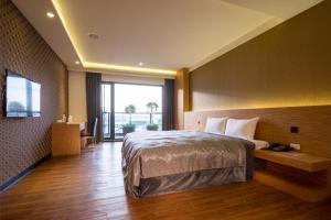 a hotel room with a bed and a large window at Ai Ni Ya Motel in Beigang