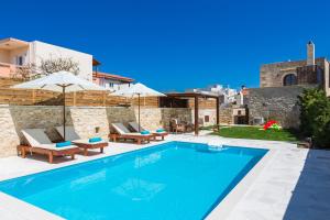 Ani Villa, authentic Cretan lifestyle في Angeliana: مسبح وكراسي ومظلات بجانب مبنى