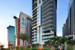 a group of tall buildings in a city with palm trees at Adagio Abu Dhabi Al Bustan in Abu Dhabi