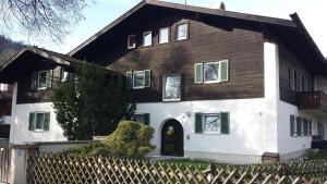 a white and brown house with a fence at Apartment Spitzenblick in Garmisch-Partenkirchen