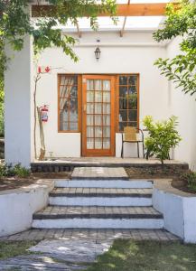 a front door of a white house with stairs at Queen Manor Boutique Guest House in Graaff-Reinet