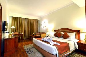 una camera d'albergo con un grande letto e una scrivania di The Bristol a Gurgaon