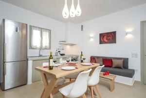 eine Küche und ein Esszimmer mit einem Holztisch und weißen Stühlen in der Unterkunft Aphrodite Luxury Apartments in Agios Prokopios