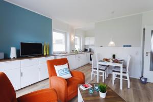 uma sala de estar com uma cadeira laranja e uma mesa em Zuhause am Meer em Büsum