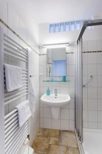 uma casa de banho branca com um lavatório e um chuveiro em Zuhause am Meer em Büsum