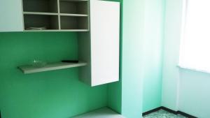 una parete verde con un armadietto bianco in una stanza di Edolo Apartment a Milano