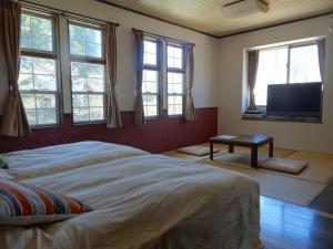 a bedroom with a bed and a flat screen tv at Gasthof Arutany in Nasu