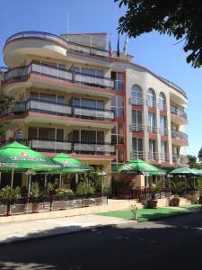 a large building with tables and green umbrellas at Family Hotel Diana in Tsarevo