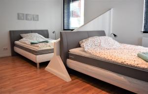 two twin beds in a room with wooden floors at Work & stay exclusive apartment in Düsseldorf