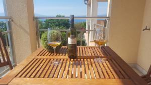 a bottle of wine and two glasses on a table at Guest House Suzana in Omišalj