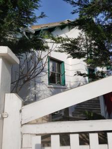 a white house with a green window and a fence at NDP Family (Ndong Du Pierrier) in Montigny-lès-Cormeilles