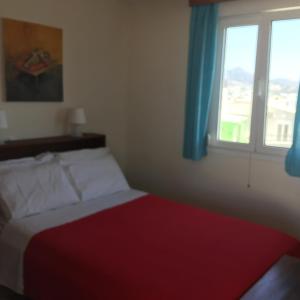 1 dormitorio con 1 cama con manta roja y ventana en Popy Apartments, en Ierápetra