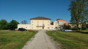 ein großes weißes Gebäude mit Autos auf einem Feld in der Unterkunft Villa Conti Zambonelli in San Giovanni in Persiceto