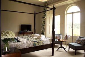 ein Schlafzimmer mit einem Himmelbett und einem TV in der Unterkunft The Falcondale Hotel & Restaurant in Lampeter