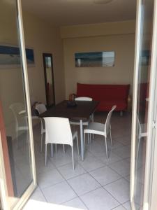 a dining room with a table and chairs and a red couch at Casa Vacanze Samira in Fondachello