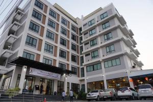 een groot wit gebouw met auto's ervoor geparkeerd bij The Sita Princess in Buriram