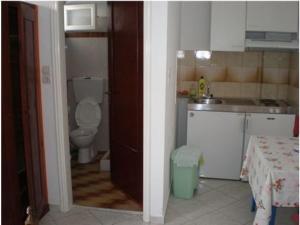a bathroom with a toilet and a sink and a kitchen at Artemis Pension in Ios Chora