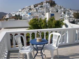 a table and chairs on a balcony with a view of a city at Artemis Pension in Ios Chora