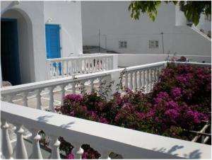 a white balcony with purple flowers on a building at Artemis Pension in Ios Chora +21 photos