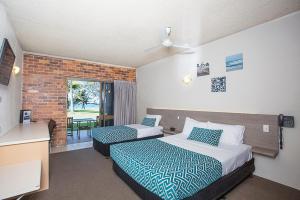 una camera d'albergo con due letti e una finestra di Sarina Beach Motel a Sarina