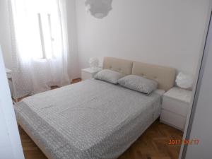 een witte slaapkamer met een bed en een spiegel bij Apartment Vlatka in Novalja