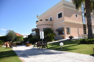 duży różowy budynek z krzesłami przed nim w obiekcie Hotel d'Altavilla w mieście Canosa di Puglia