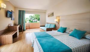 
a hotel room with two beds and a television at Invisa Hotel Club Cala Blanca in Es Figueral Beach
