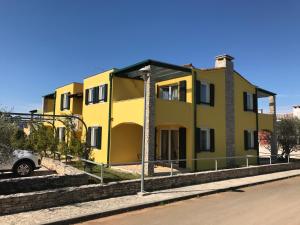 une maison jaune sur le côté d'une route dans l'établissement Apartmani Svjetionik, à Umag