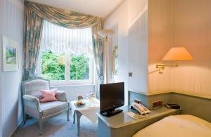 een slaapkamer met een bed, een bureau en een stoel bij Privat-Hotel Villa Aurora in Bad Neuenahr-Ahrweiler