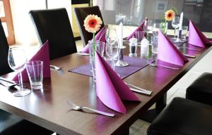 une table en bois avec des serviettes violettes au-dessus dans l'établissement Hotel zwei&vierzig, à Vallendar