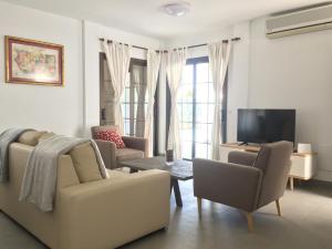 sala de estar con sofá, sillas y TV en Villas Las Maretas, en Costa Teguise