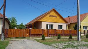 ein Haus mit einem Holzzaun in der Unterkunft Ladik Vendégház in Tiszafüred