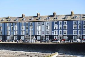 un gran edificio azul con coches estacionados frente a él en Awel Mor 3 Luxury Apartment, en Aberystwyth