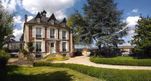 a large brick house with a tree in front of it at Le Jardin Des Erables in Saint-Marcel