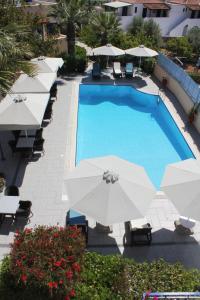 a swimming pool with white umbrellas and chairs and a pool at Vanas Apartments in Spetses