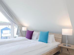 Un dormitorio con una cama blanca con almohadas moradas y azules en Haus Marinas, en Helgoland