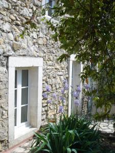 a stone building with a window and flowers in front of it at Au Fil de Soi in Vézénobres