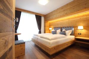a bedroom with a large bed with a wooden wall at DOLOMITES B&B - Suites, Apartments and SPA in Tesero