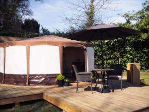 a wooden deck with a table and an umbrella at The Old Dairy Farm in Emsworth