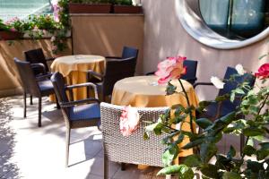 リッチョーネにあるHotel Gabbianoの- パティオ(花の飾られた椅子とテーブル2台付)