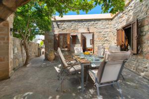 una mesa y sillas frente a una casa de piedra en Villa Claudia in Lardos en Lardos