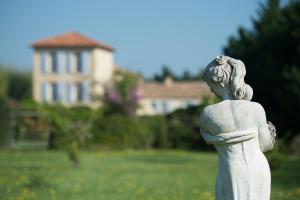 a statue of a woman in a field with a house in the background at Les Carmes and spa in Le Thor