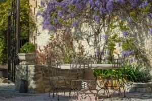 a table and chairs in a garden with purple flowers at Les Carmes and spa in Le Thor