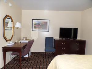 a hotel room with a desk and a bed and a mirror at Executive Inn Chillicothe in Chillicothe