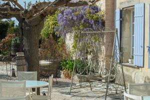 a table and chairs and a tree with purple flowers at Les Carmes and spa in Le Thor