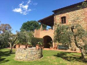 a house with a stone wall and a yard at Fattoria Cirene in Follonica